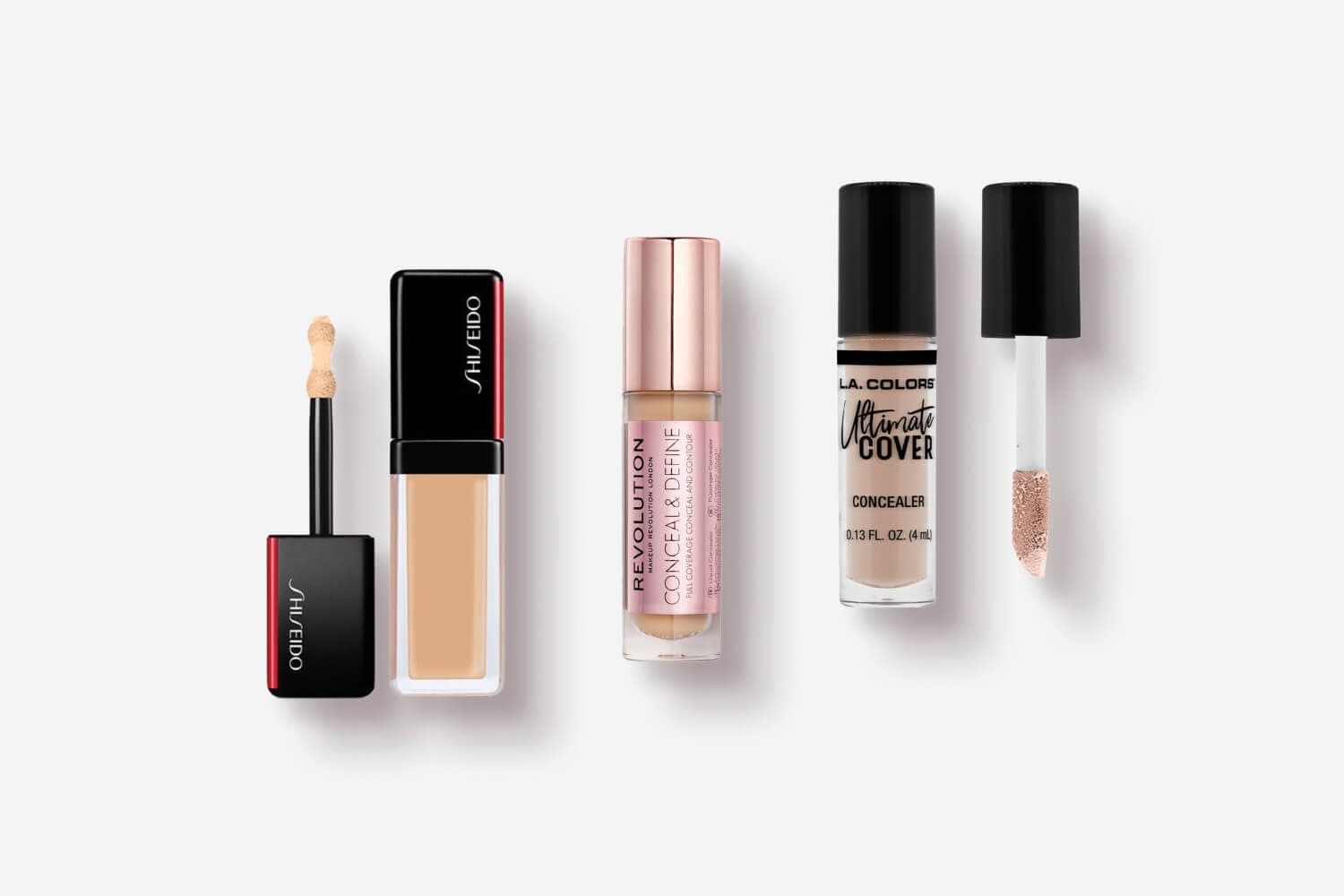 Three open liquid concealers on grey: Shiseido with its cushion applicator, Makeup Revolution Conceal & Define, and L.A. Colors Ultimate Cover. Three open liquid concealers on grey: Shiseido with its cushion applicator, Makeup Revolution Conceal & Define, and L.A. Colors Ultimate Cover.
