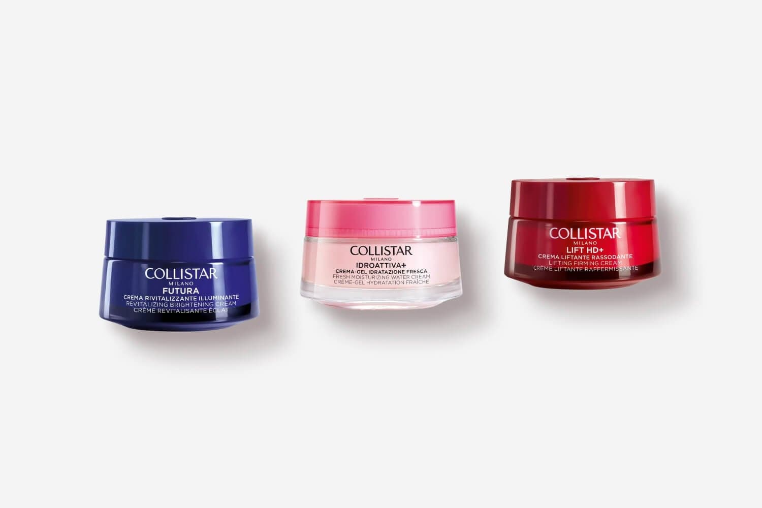 Three Collistar face cream jars on grey: blue Futura Revitalizing Brightening, pink Idroattiva+ Water Cream, red Lift HD+ Lifting Firming. Three Collistar face cream jars on grey: blue Futura Revitalizing Brightening, pink Idroattiva+ Water Cream, red Lift HD+ Lifting Firming.