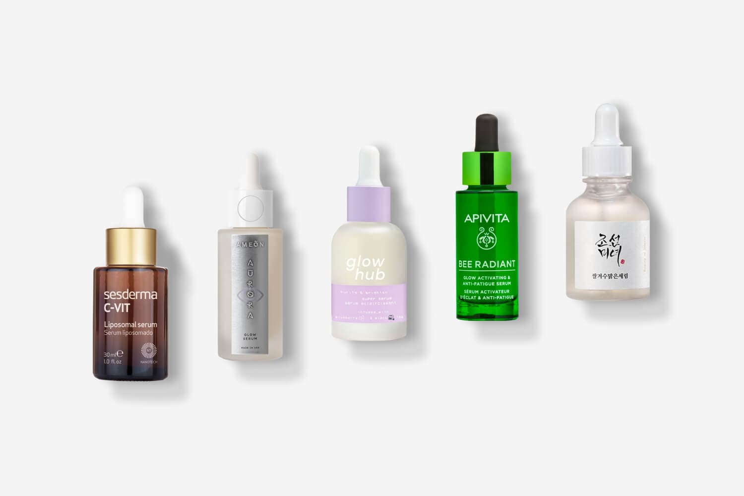 Five serum bottles in a row: Sesderma C-VIT Liposomal, Ameon Aurora Glow, Glow Hub Super Serum, Apivita Bee Radiant and Beauty of Joseon. Five serum bottles in a row: Sesderma C-VIT Liposomal, Ameon Aurora Glow, Glow Hub Super Serum, Apivita Bee Radiant and Beauty of Joseon.
