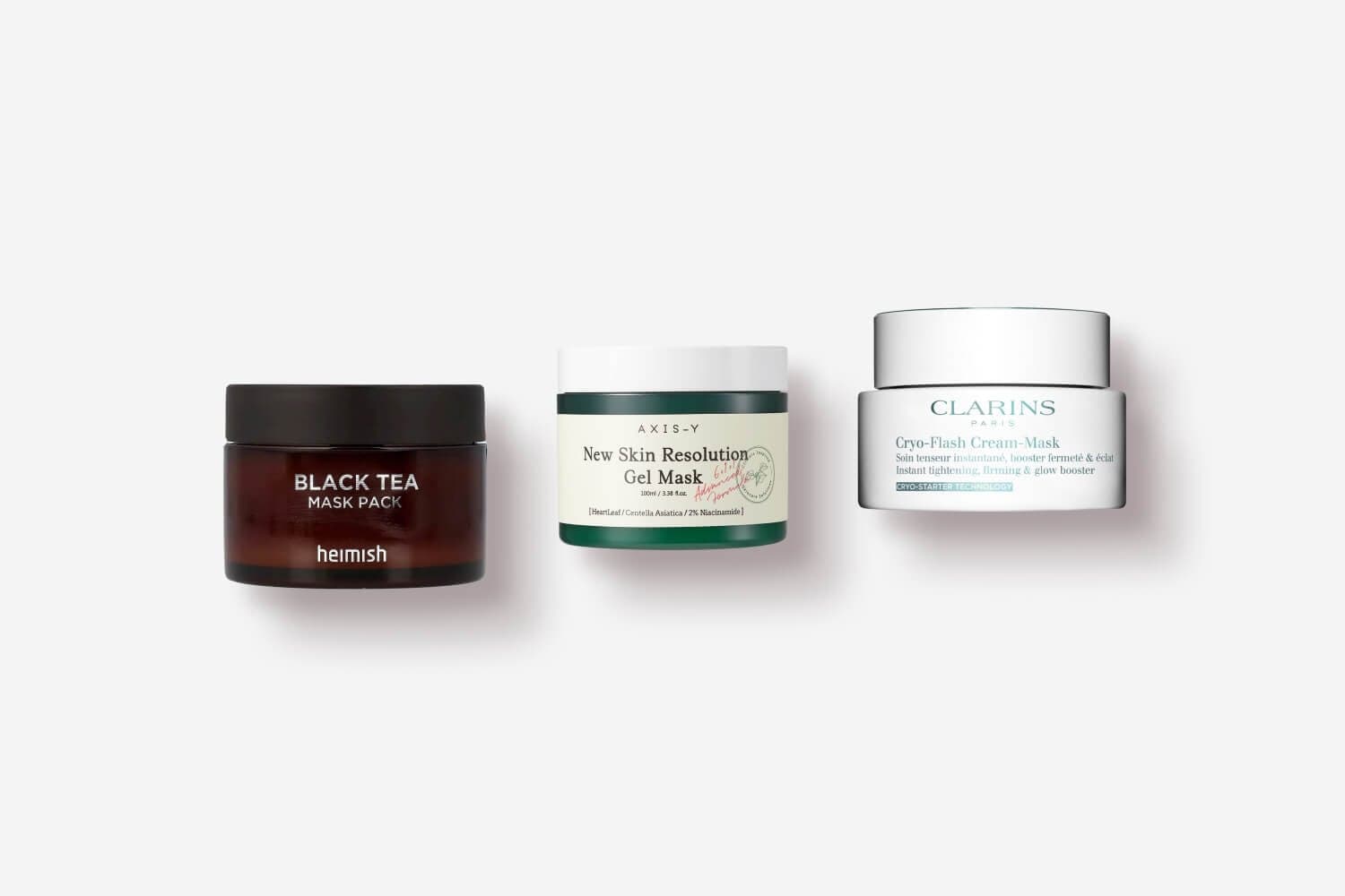 Heimish Black Tea Mask Pack, AXIS-Y New Skin Resolution Gel Mask and Clarins Cryo-Flash Cream-Mask jars in a row. Heimish Black Tea Mask Pack, AXIS-Y New Skin Resolution Gel Mask and Clarins Cryo-Flash Cream-Mask jars in a row.